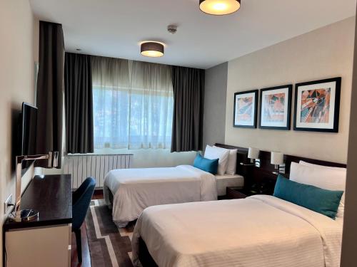 a hotel room with two beds and a television at Bosmal Arjaan by Rotana in Sarajevo