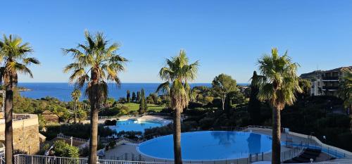 a view of a resort with palm trees at Appartement 4 pers Cap Estérel centre du village CLIM WIFI in Saint-Raphaël