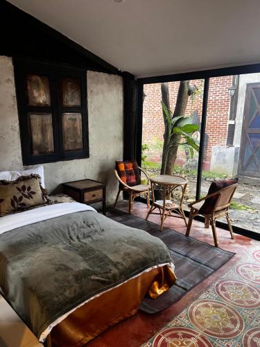 Ban Nong WaiにあるKad Sala Homestayのベッドルーム(ベッド1台、椅子、大きな窓付)