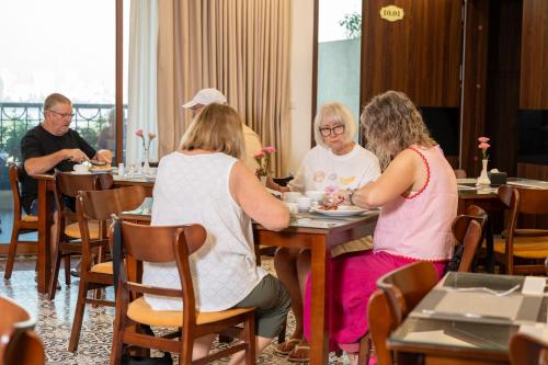 a group of people sitting at tables in a restaurant at Luxe Paradise Premium Hotel Nguyen Khac Hieu in Hanoi