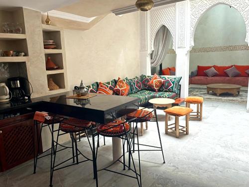 Riad Nora - Confort, Calme & Sécurité في مراكش: غرفة معيشة مع أريكة وطاولات وكراسي
