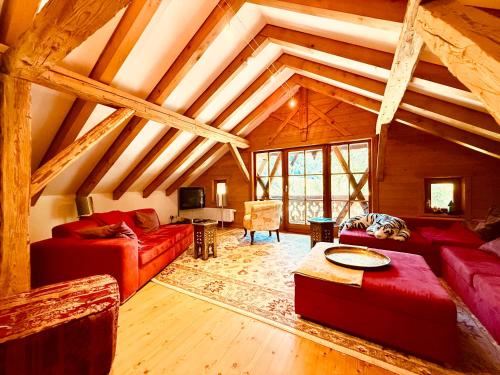 a living room with red couches and a wooden ceiling at Haus Freistabl - Uriges Bauernhaus für 6 Personen mit Sauna & Bergblick im Ötztal in Sölden