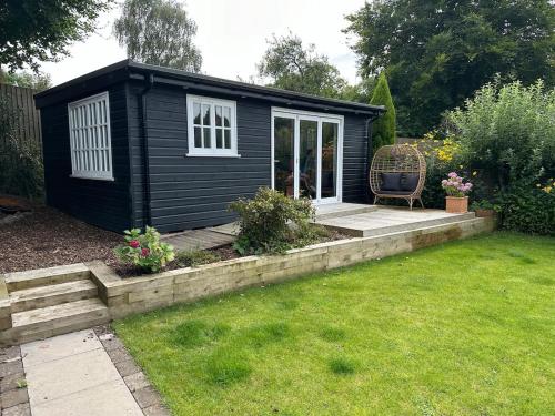 a black shed with a chair in a yard at Peaceful Garden Cottage in Birmingham