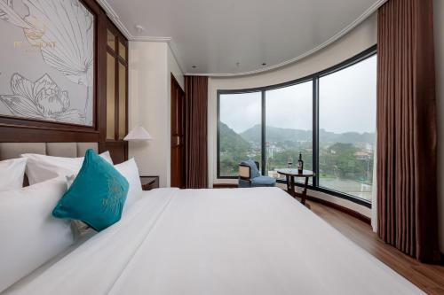 a bedroom with a large bed with a large window at De La Mont Hotel Ha Giang in Ha Giang