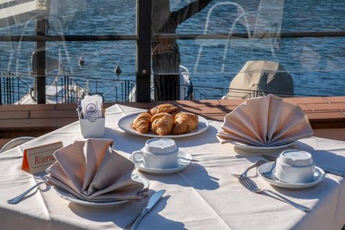 a table with plates of croissants and cups and utensils at Hotel Lenno in Lenno