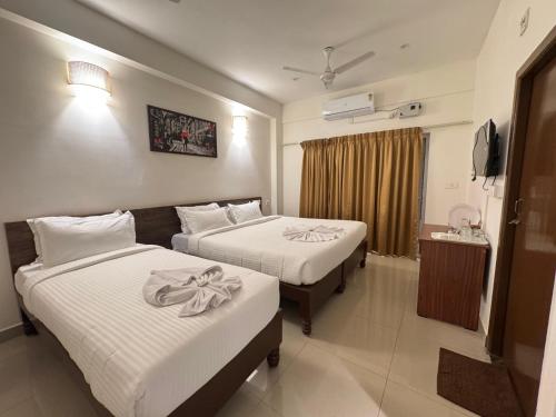 une chambre d'hôtel avec deux lits et une télévision dans l'établissement La Millionaire Resort, à Auroville