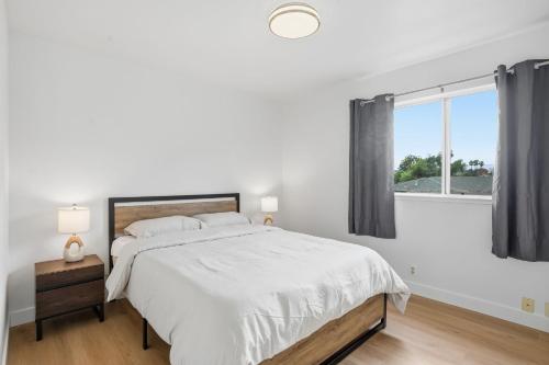 ein weißes Schlafzimmer mit einem großen Bett und einem Fenster in der Unterkunft Modern 2BR Unit with Covered Parking in Santa Clara apts in Santa Clara