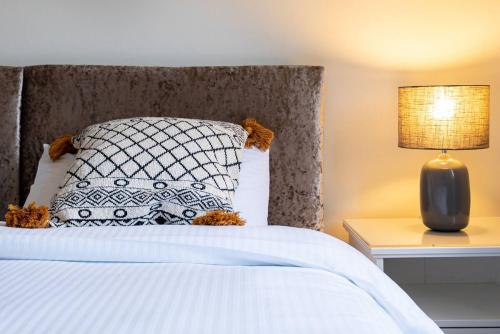 ein Schlafzimmer mit einem Bett mit Kissen und Lampe in der Unterkunft 4 Bedroom Townhouse In Stirling in Stirling