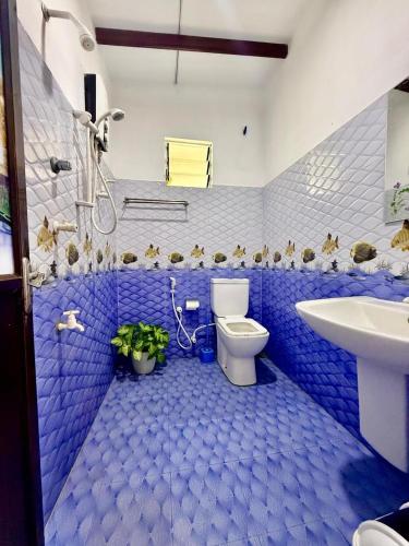 a blue bathroom with a toilet and a sink at Thusitha s nest in Dickwella