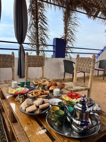 ein Tisch mit Tellern voller Essen in der Unterkunft Waves House Tamraght - Surf & Chill Hostel in Tamraght Ouzdar
