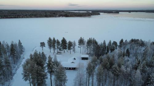 a house in the snow next to a lake at Aurora Haven in Vanttauskoski