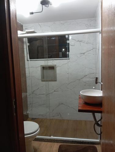 a bathroom with a sink and a glass shower at Aconchego Valença loft in Nova Friburgo