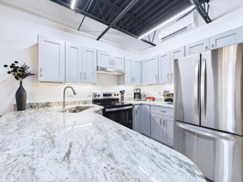 a kitchen with white cabinets and a marble counter top at Chic Loft Retreat Near Port Canaveral -Unit 202 in Cape Canaveral
