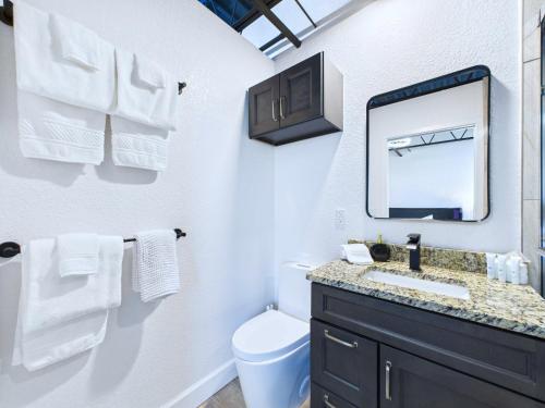 une salle de bain blanche avec un lavabo et un miroir dans l'établissement Bright Modern Loft By Port & Beaches -unit 206, à Cap Carnaveral
