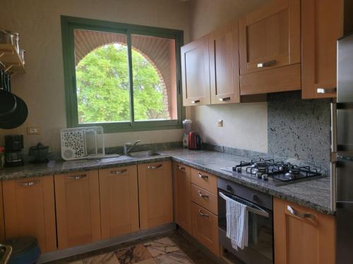 马拉喀什Palmeraie village 2 , les jardins de la palmeraie 2的厨房配有木质橱柜、水槽和窗户