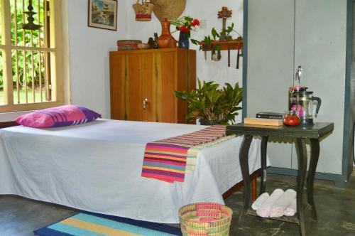 a bedroom with a bed and a table with a table at EcoBlueprint Garden in Pannala