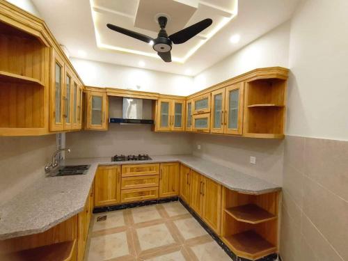 cocina con armarios de madera y ventilador de techo en Vista Lodge Guest House, en Islamabad