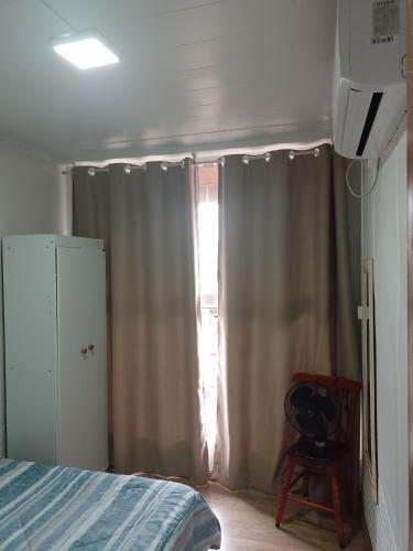 a bedroom with a bed and a window with curtains at Casa container in São Lourenço do Sul
