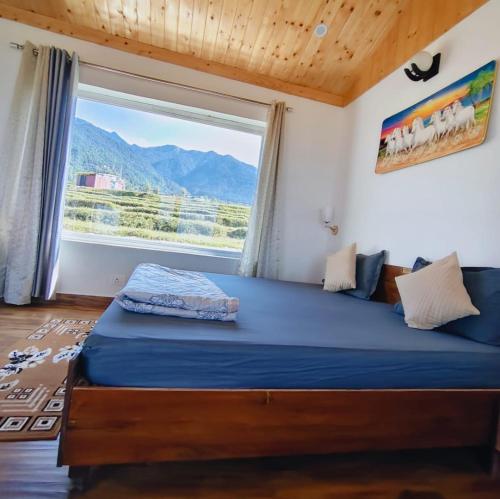 ein Bett in einem Zimmer mit einem großen Fenster in der Unterkunft Sunshine Cottages in Bir