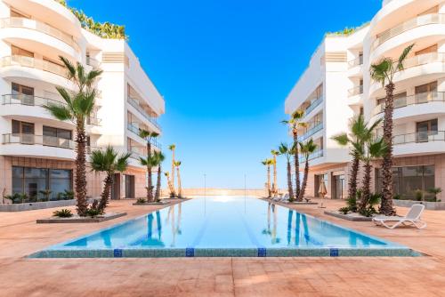 Oulad AkkouにあるAzur Apartment pool & designのヤシの木が茂る建物の前にあるスイミングプール