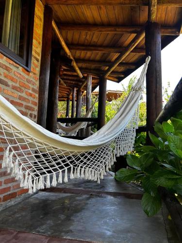 a hammock hanging from a porch of a house at Encanto do Mar Praia do Rosa in Praia do Rosa