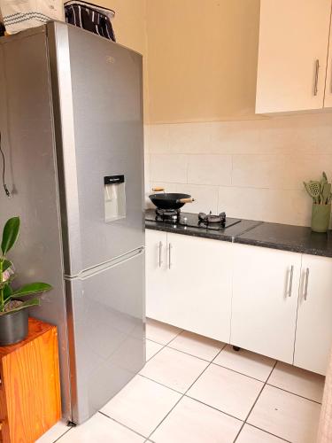 une cuisine avec des armoires blanches et un réfrigérateur en acier inoxydable dans l'établissement Mini Cottage Home, à Johannesbourg