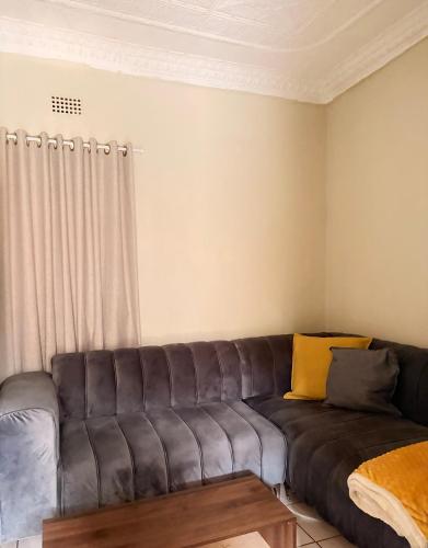 a couch in a living room with a window at Mini Cottage Home in Johannesburg