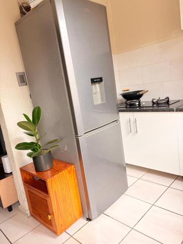 a stainless steel refrigerator in a kitchen with a potted plant at Mini Cottage Home in Johannesburg