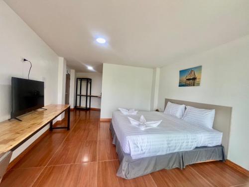 a bedroom with a bed and a flat screen tv at Lucky 9 Airport Hotel Phuket in Nai Yang Beach