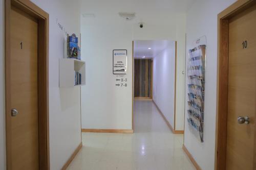 einen Flur in einem Gebäude mit weißen Wänden und einer Tür in der Unterkunft Hotel Las Palmas Urban Center in Las Palmas de Gran Canaria