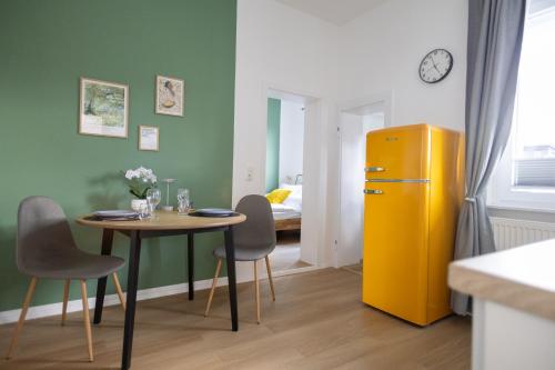 d'une salle à manger avec une table et un réfrigérateur jaune. dans l'établissement Wohlfühl-Apartment Waldschimmer, Extra Komfort für Business & Urlaub, à Unterlüß