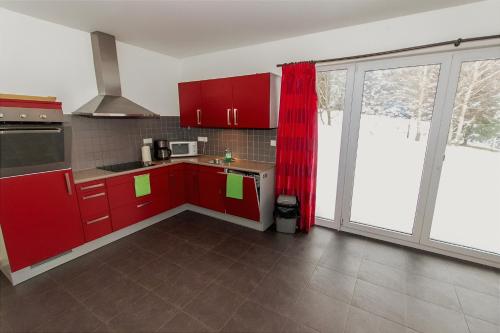 cocina con armarios rojos y ventana grande en Villa Slupečná, en Lipno nad Vltavou