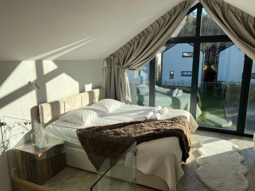 UliniaにあるNATURA APARTAMENTY Eraのベッドと大きな窓のある寝室