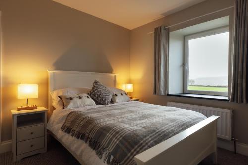 a bedroom with a bed with two lamps and a window at Homely Cottage - Beaches, Costal walks, Castles in Newchapel