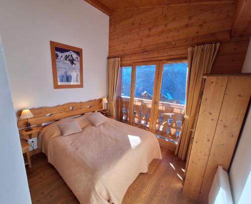 a bedroom with a bed and a large window at Les Airelles A21 in Les Menuires
