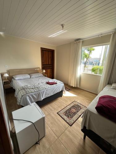 une chambre d'hôtel avec deux lits et une fenêtre dans l'établissement Pousada Avenida, à Tibagi