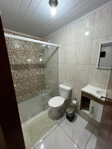 une salle de bains avec douche, toilettes et lavabo dans l'établissement Pousada Avenida, à Tibagi