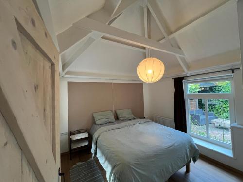 a bedroom with a bed and a large window at Diedjestee in Westdorp