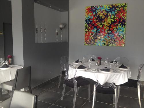 a dining room with white tables and chairs and a painting at Sous Les Pins in Étoile-sur-Rhône