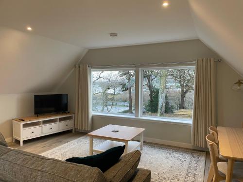 a living room with a couch and a table and a window at Adalienes Retreat Flat 3 in Portree