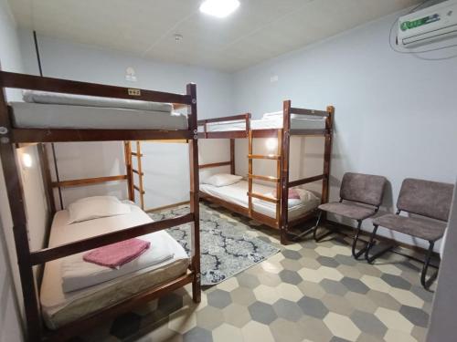 a room with three bunk beds and two chairs at Caravan Hostel in Tashkent International Airport