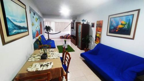 ein Wohnzimmer mit einem Tisch und einem blauen Sofa in der Unterkunft Alquilo apto 8 personas en Caribbean Suit - Tucacas in Los Corales