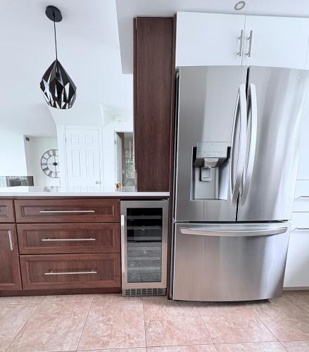 a kitchen with a stainless steel refrigerator and wooden cabinets at La maison de la Baie in Chambord