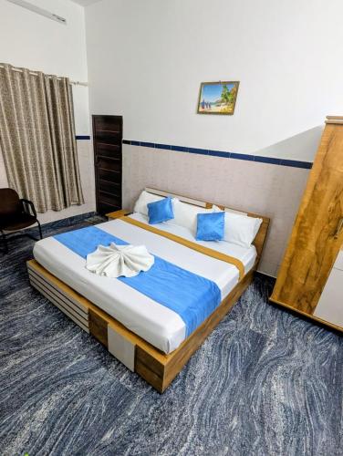 a bedroom with a large bed with blue sheets at kollam Beach Resort in Kollam
