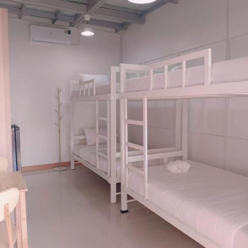 zwei weiße Etagenbetten in einem weißen Zimmer in der Unterkunft Convenient Resort in Lat Krabang