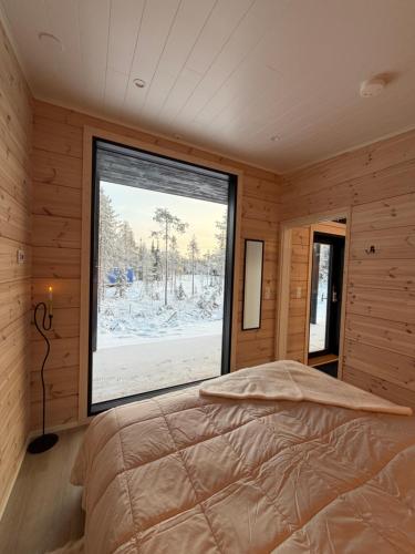 a bedroom with a bed and a large window at Modern VillaJoenhelmi with jacuzzi and sauna in Kuusamo