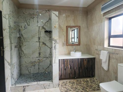 a bathroom with a shower and a sink at Lakefield Hotel in Benoni