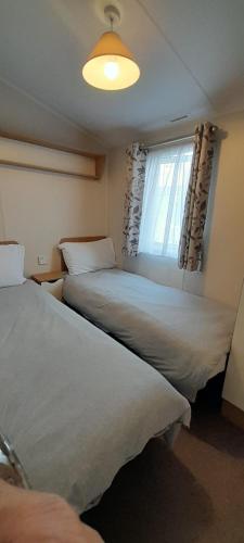 a bedroom with two beds and a window with curtains at Willerby Escapes in Lytchett Minster