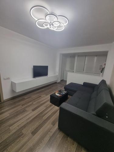 a living room with a black couch and a tv at Ezzely apartment ParkLake in Bucharest
