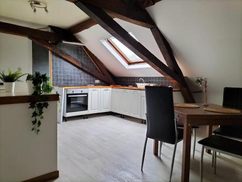 a kitchen with white cabinets and a table with chairs at studio de l'ancienne gendarmerie in Mons